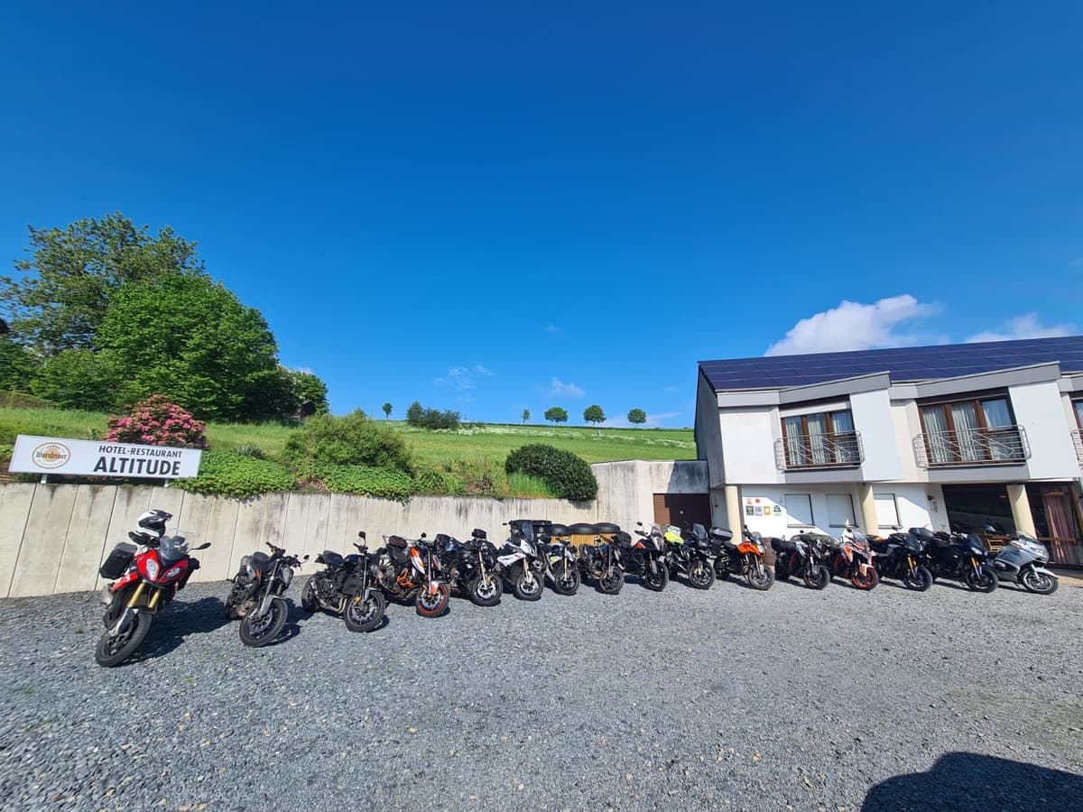 Een lange rij motoren op het grind voor Hotel-Restaurant Altitude, onder een strakblauwe lucht.